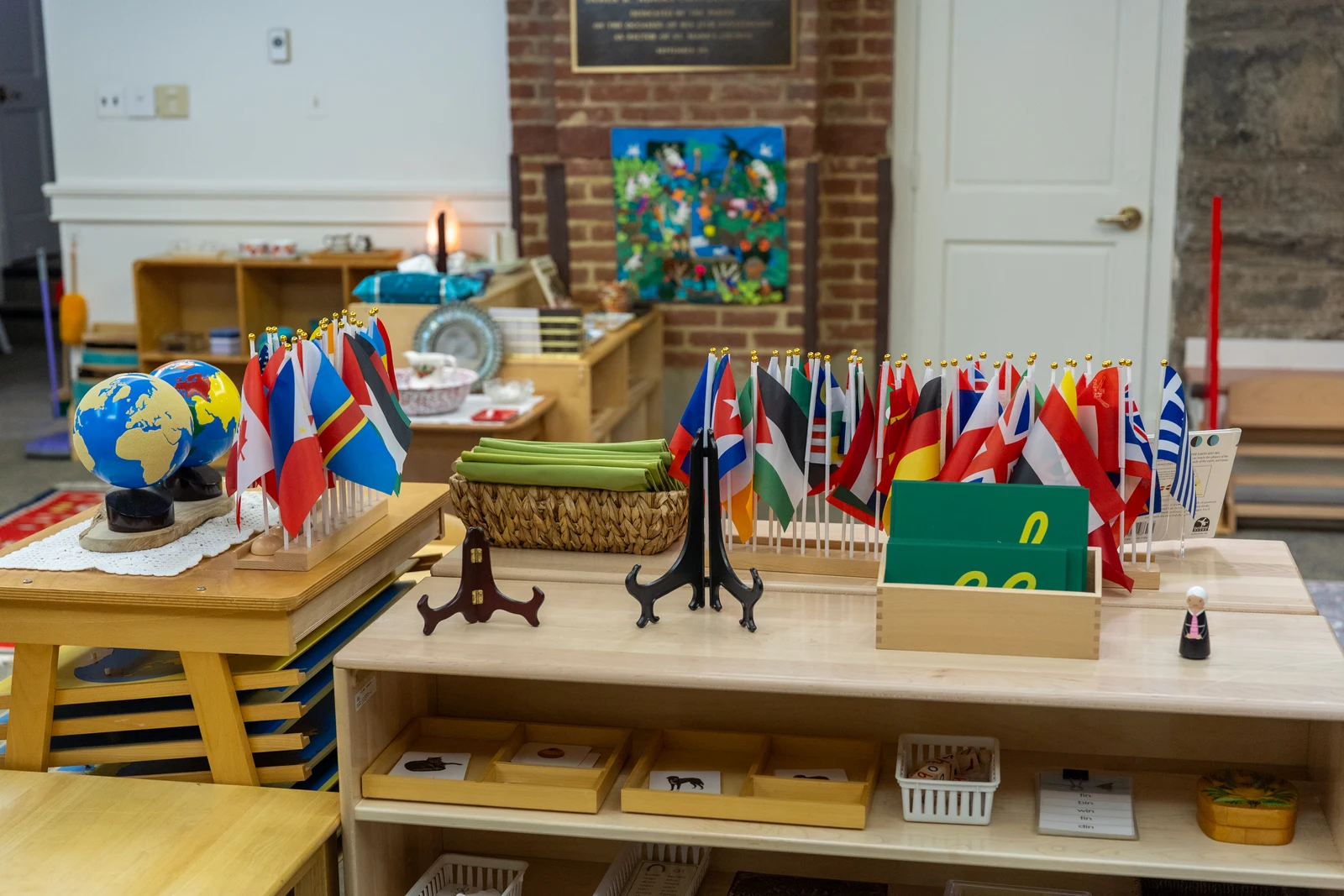 A Montessori Primary classroom geography shelf with world flags and globes at Starling Montessori School on Capitol Hill